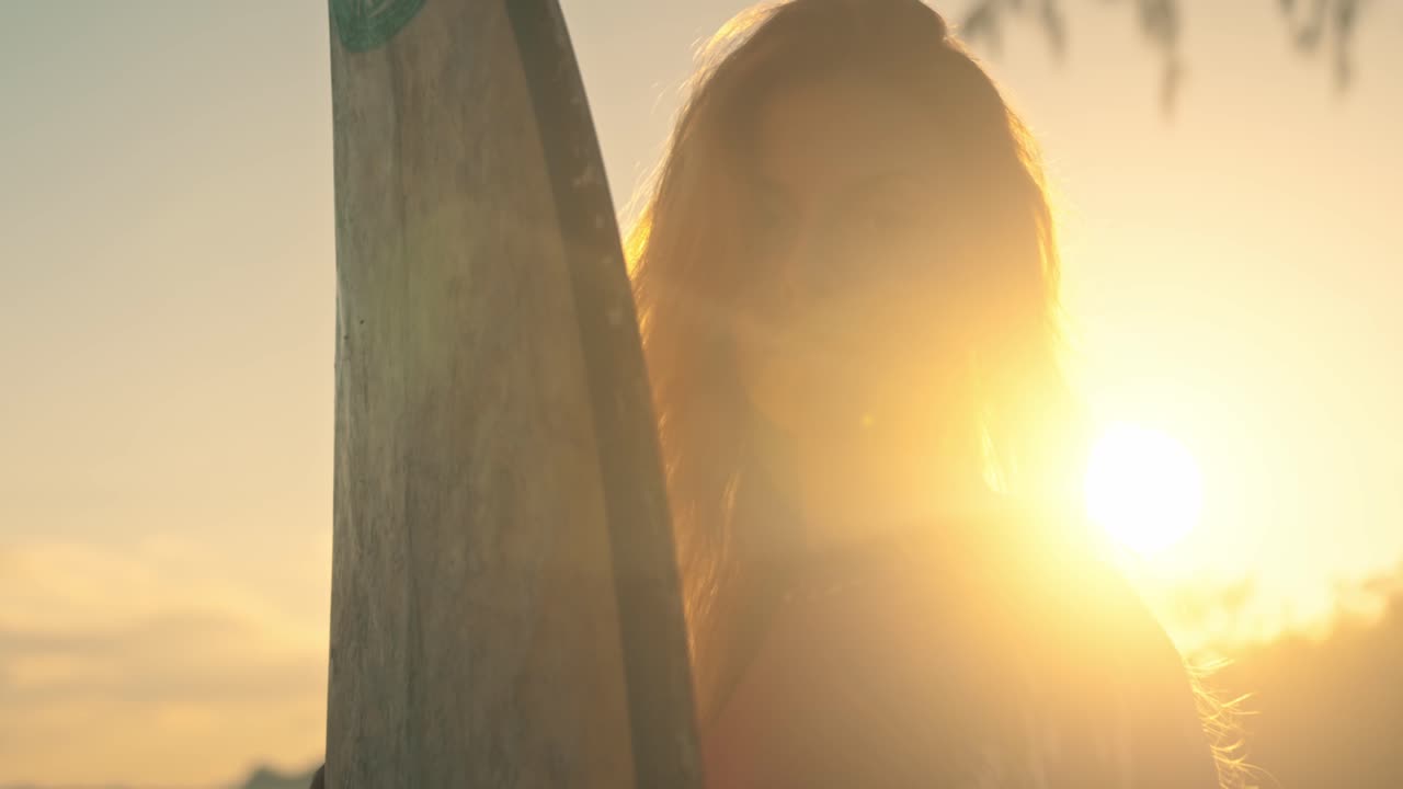 해가 지는 동안 서프보드 를 들고 있는 여자