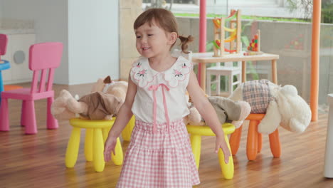 one cheerful playful little girl playing with teddy bears inside playroom - slow motion