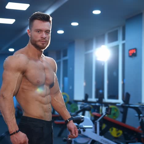 hot handsome strong guy man without a shirt against gym background. male beauty concept. slow motion