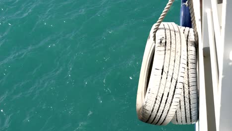 white-painted car tire, attached as a bumper on the ferry's side