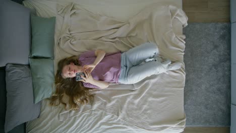 woman lying in bed using phone