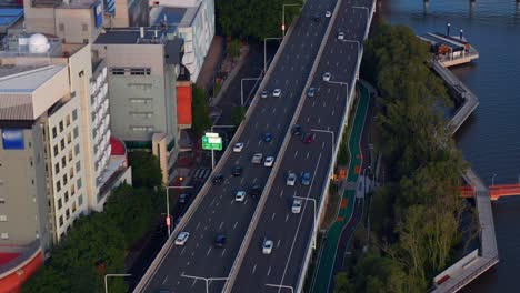 Vehículos-Circulando-Por-La-Autopista-Del-Pacífico-Y-El-Puente-Captain-Cook-Que-Cruza-El-Río-Brisbane-Al-Atardecer-En-Australia