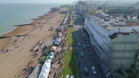 Flying-over-sea-shore,-people,-buildings-and-street-market