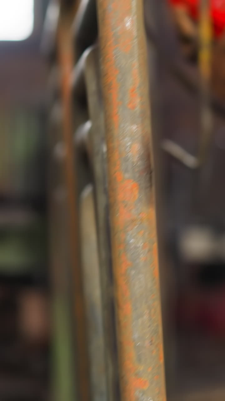 Worker in gloves takes rust metal frame out of hook in plant storage closeup. Workman stacks bent steel elements of heating system slow motion