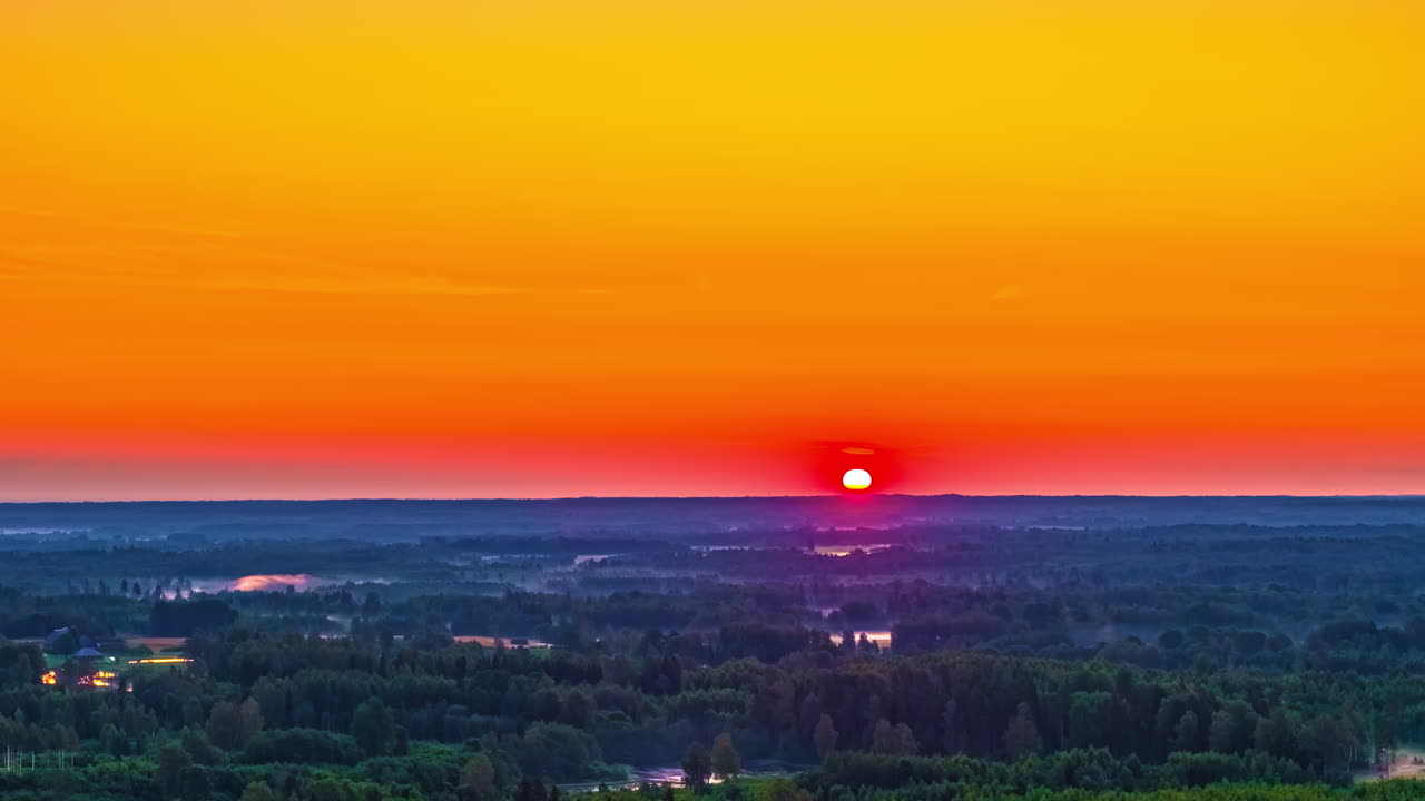 Fiery orange sunrise glow over distant farmland and fields, space for text in sky above