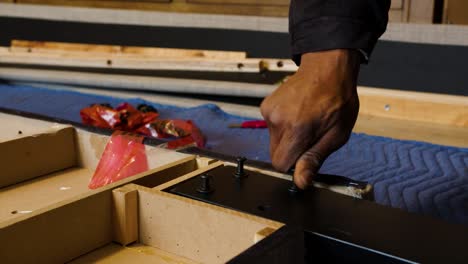 close action shot of african american mans hand screwing into wooden board furniture parts