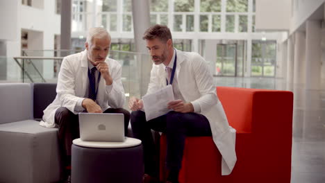 Two-Doctors-Having-Meeting-In-Hospital-Reception-Area