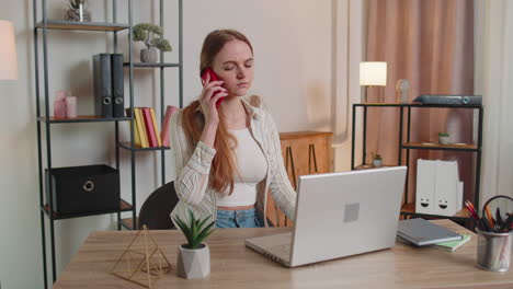 Young-woman-using-laptop-computer-sitting-on-sofa-working,-online-shopping-from-home-office