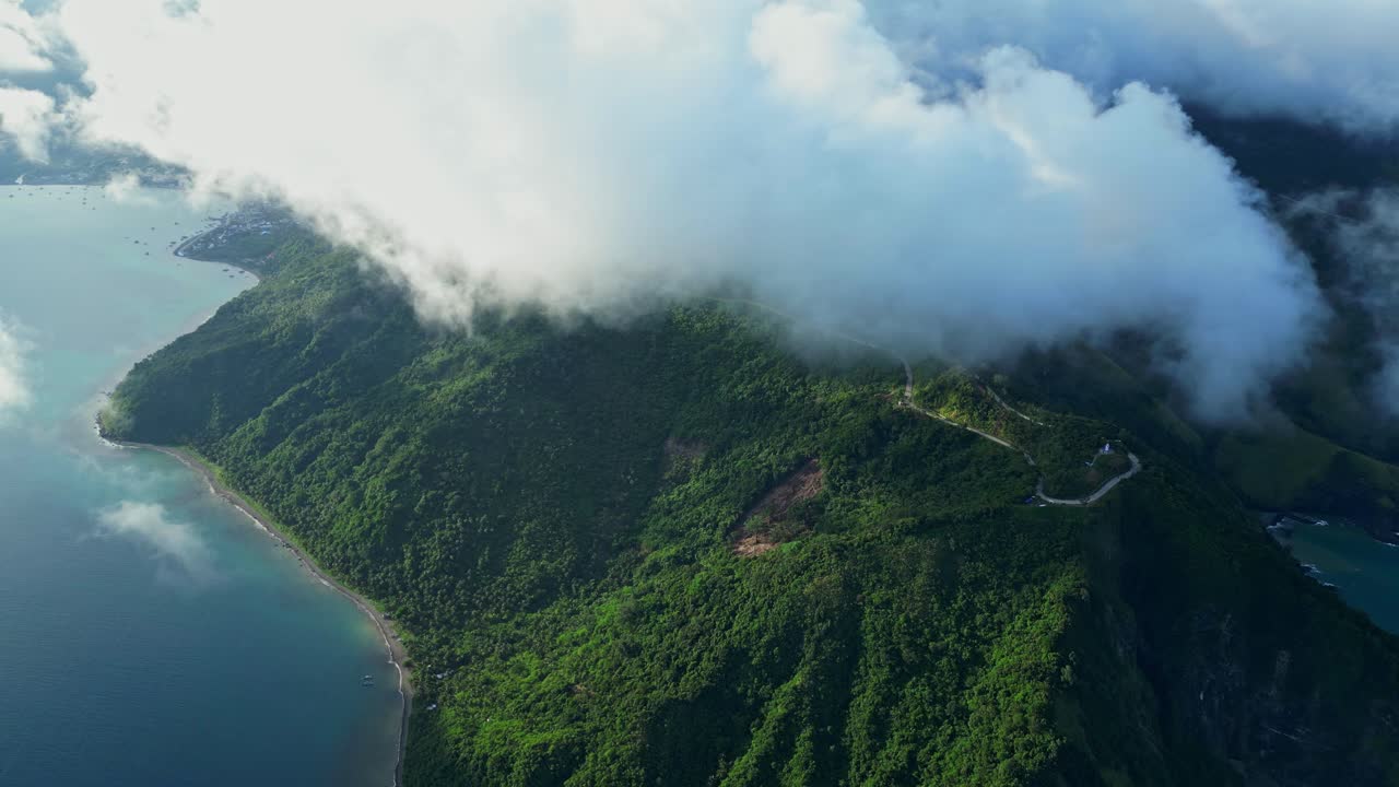 Slow pan aerial drift in Dingalan, Aurora, gliding smoothly across lush green hills and rugged coastline as turquoise waves roll against the cliffs under a wide open sky