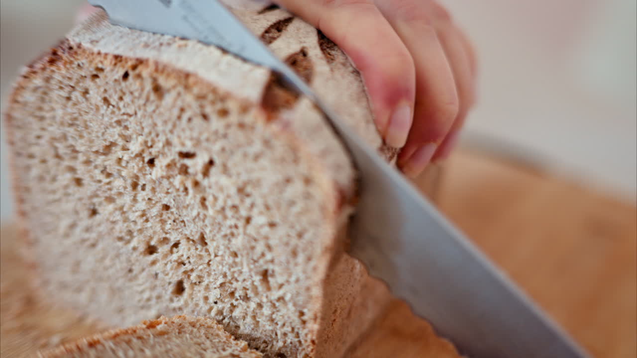 Woman cutting rye sourdough bread on a wooden cutting board