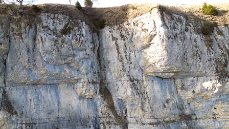 aerial ascent closeup of rock cliff face and meadow above, wandfluh solothurn, switzerland