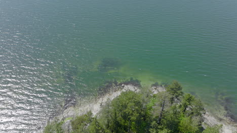 Aerial-of-rocky-shore-of-island-in-Puget-Sound-in-an-inlet-of-the-Salish-Sea-in-Bellingham,-Washington-with-a-pan-around-the-island