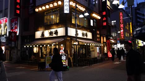 pedestrians walking past illuminated urban buildings