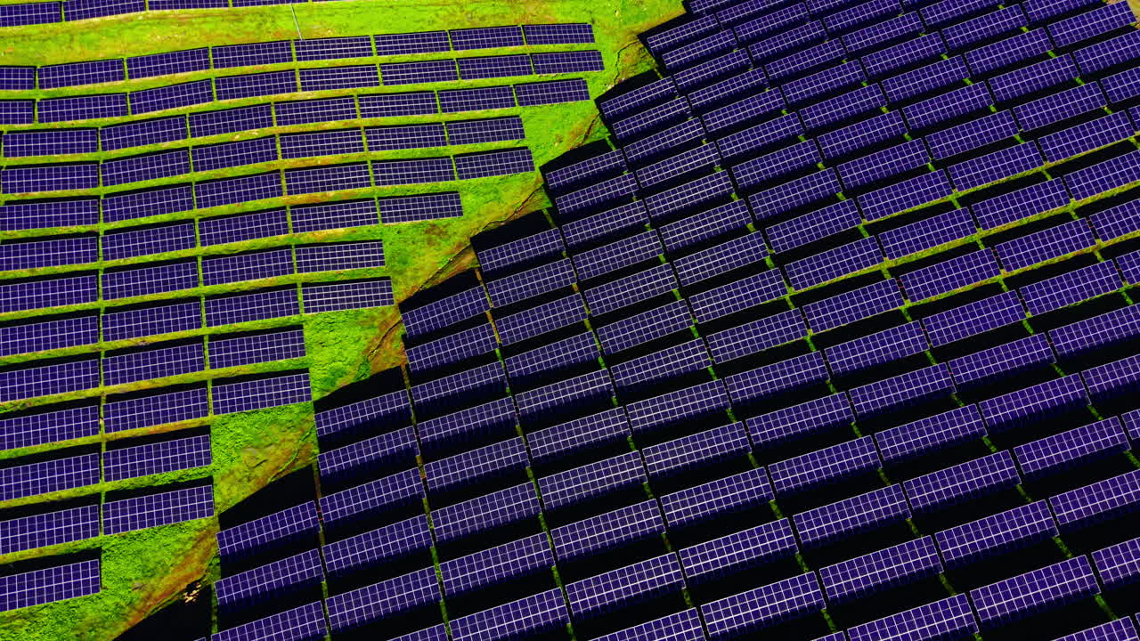 Vista aerea dall'alto di pannelli solari disposti in una griglia geometrica. I pannelli blu creano un contrasto con l'erba verde. Struttura organizzata e modelli ripetuti di array fotovoltaici