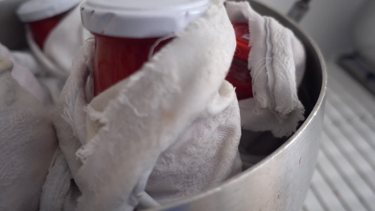 disparo de cerca de botellas de vidrio de salsa de tomate siendo hervidas para esterilizar el contenido