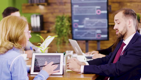 middle age female team lider standing near the table giving direction to her young coworker