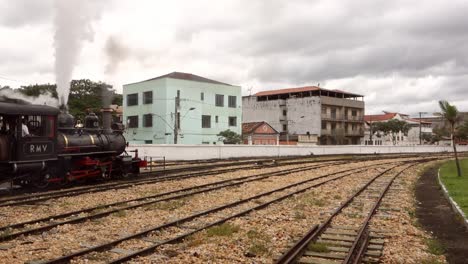 Alter-Dampfzug,-Der-Vom-Bahnhof-In-Der-Stadt-Abfährt-Und-Rauch-In-Der-Luft-Freisetzt