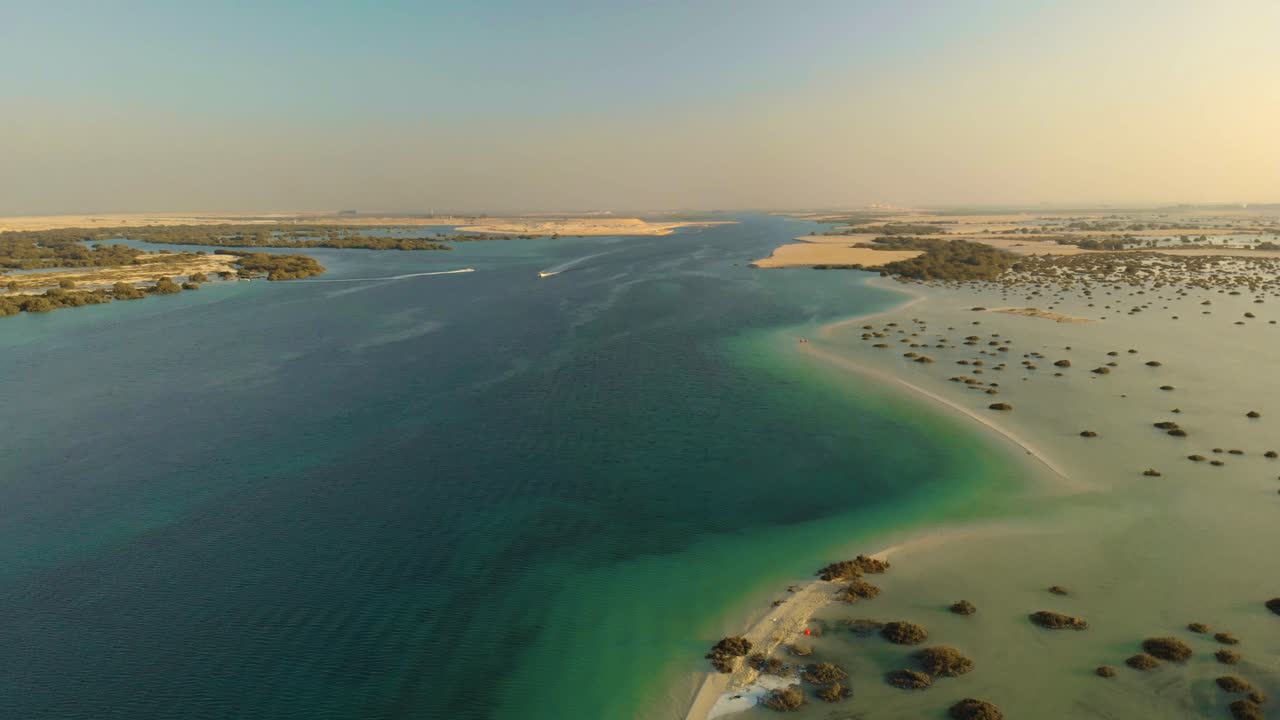 Drone luftpanorering hen over turkise havfloder delt af sandbanke med mangrover