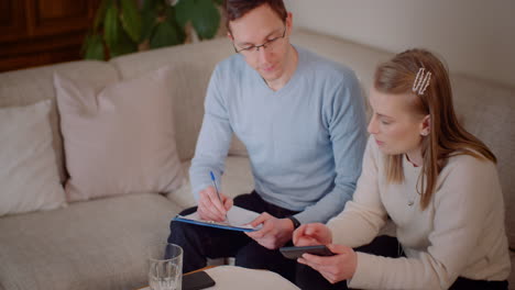 People having a discussion while one writes on a clipboard and another uses a smartphone