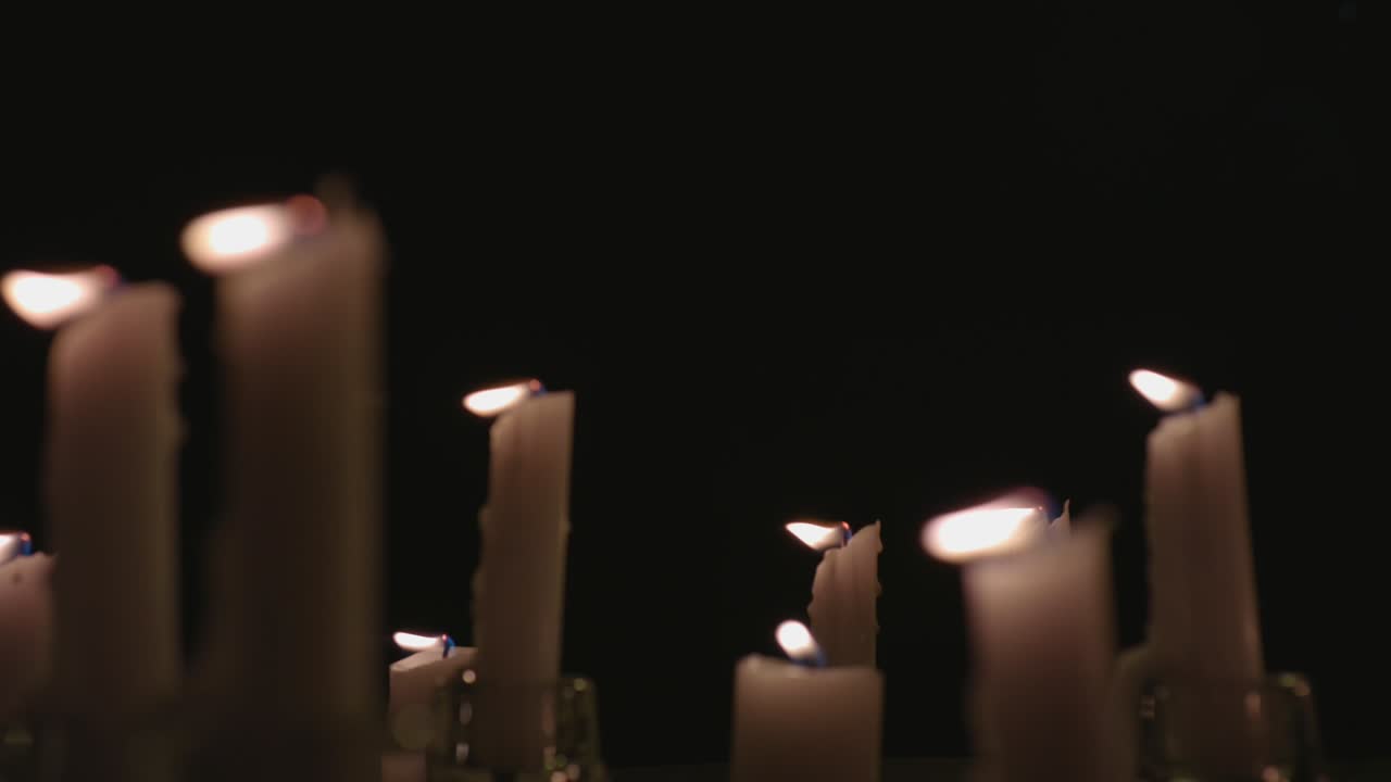 Un primissimo piano di candele bianche accese con uno sfondo nero