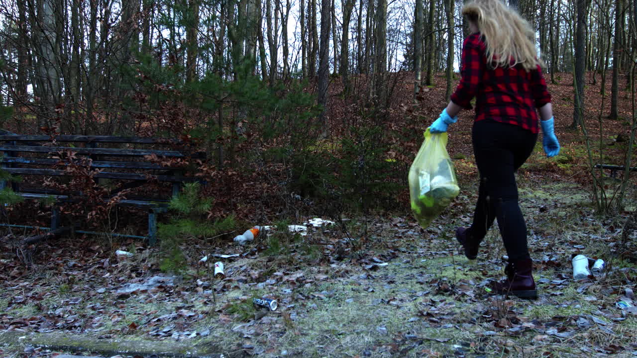 Female volunteer collects garbage in forest