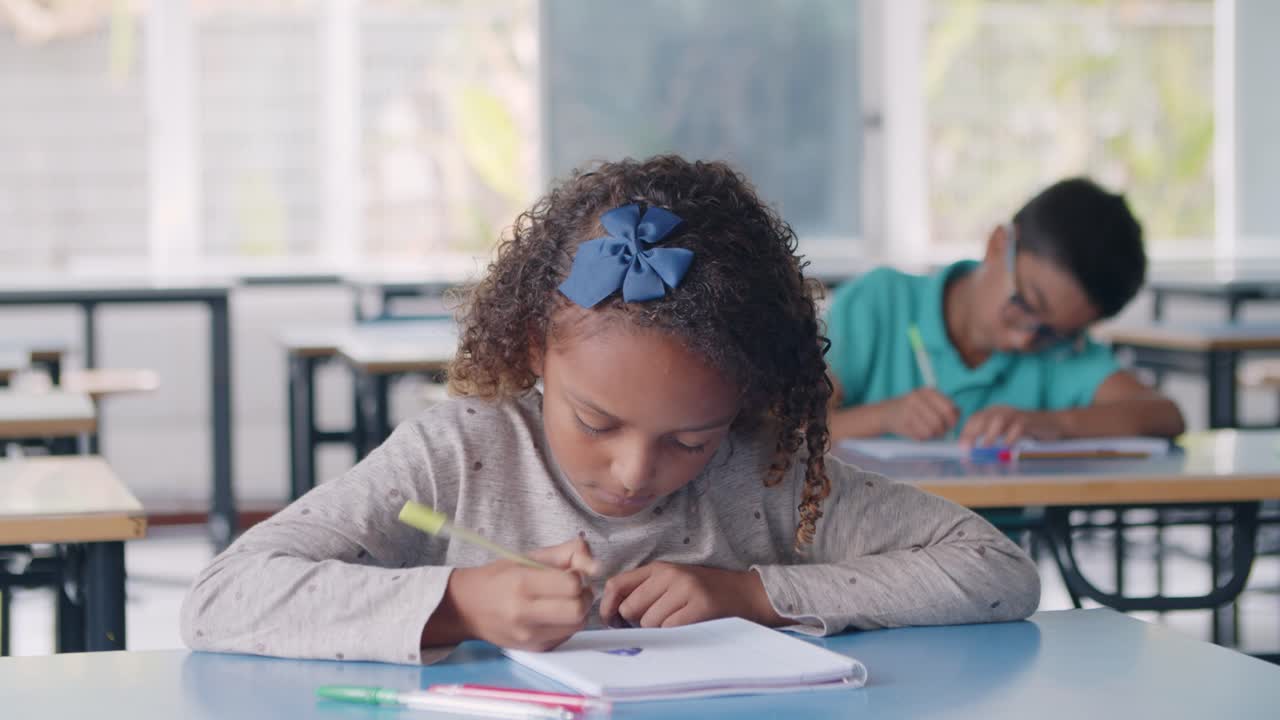 Focused Black pupil girl using pen to write the exercises