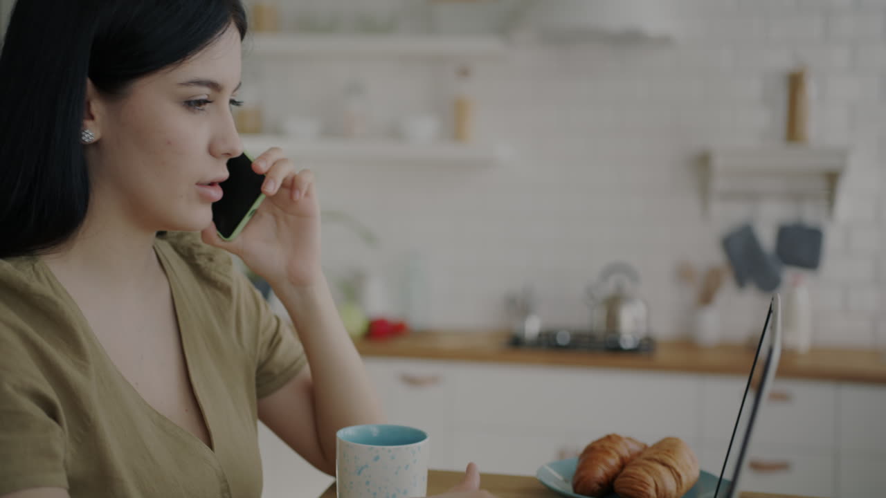 Woman working from home, having a phone call and breakfast