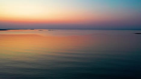 Vista-Aérea-Por-Drones-De-La-Colorida-Puesta-De-Sol-Del-Océano-En-Saco,-Maine,-Con-Colores-Brillantes-Que-Se-Reflejan-En-Las-Tranquilas-Olas-Del-Mar-A-Lo-Largo-De-La-Costa-Atlántica-De-Nueva-Inglaterra