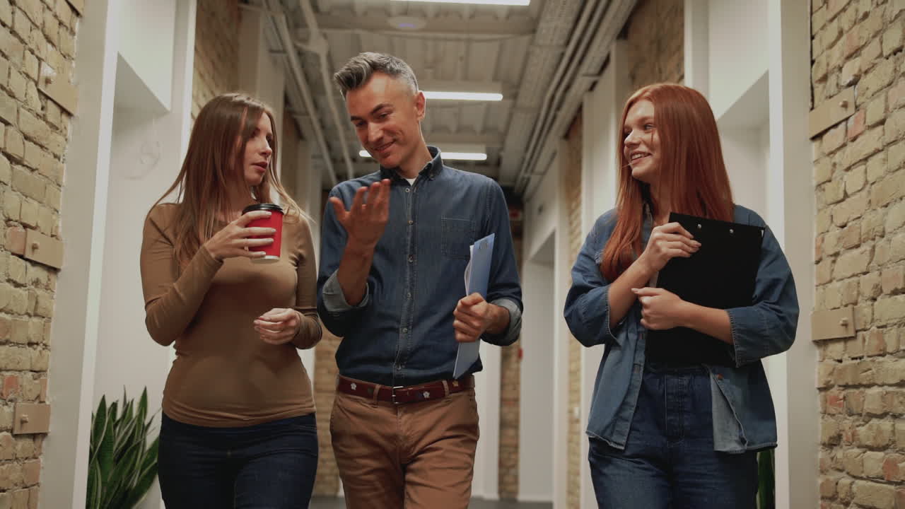 mujer de negocios y hombre maduro caminando hacia la cámara en un pasillo. la gente va a una reunión de trabajo.