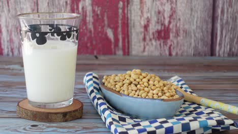 soy milk and raw soybeans on a rustic wooden table