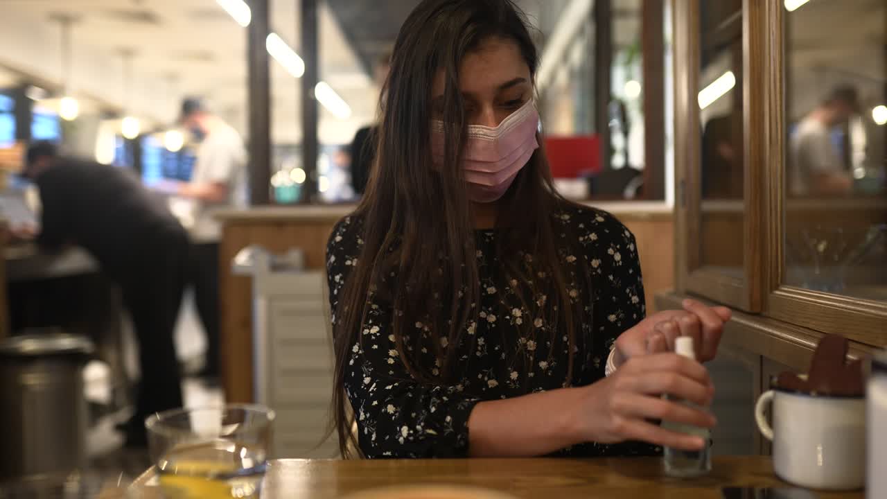 레스토랑에서 마스크를 착용하고 손 소독제를 사용하는 여성