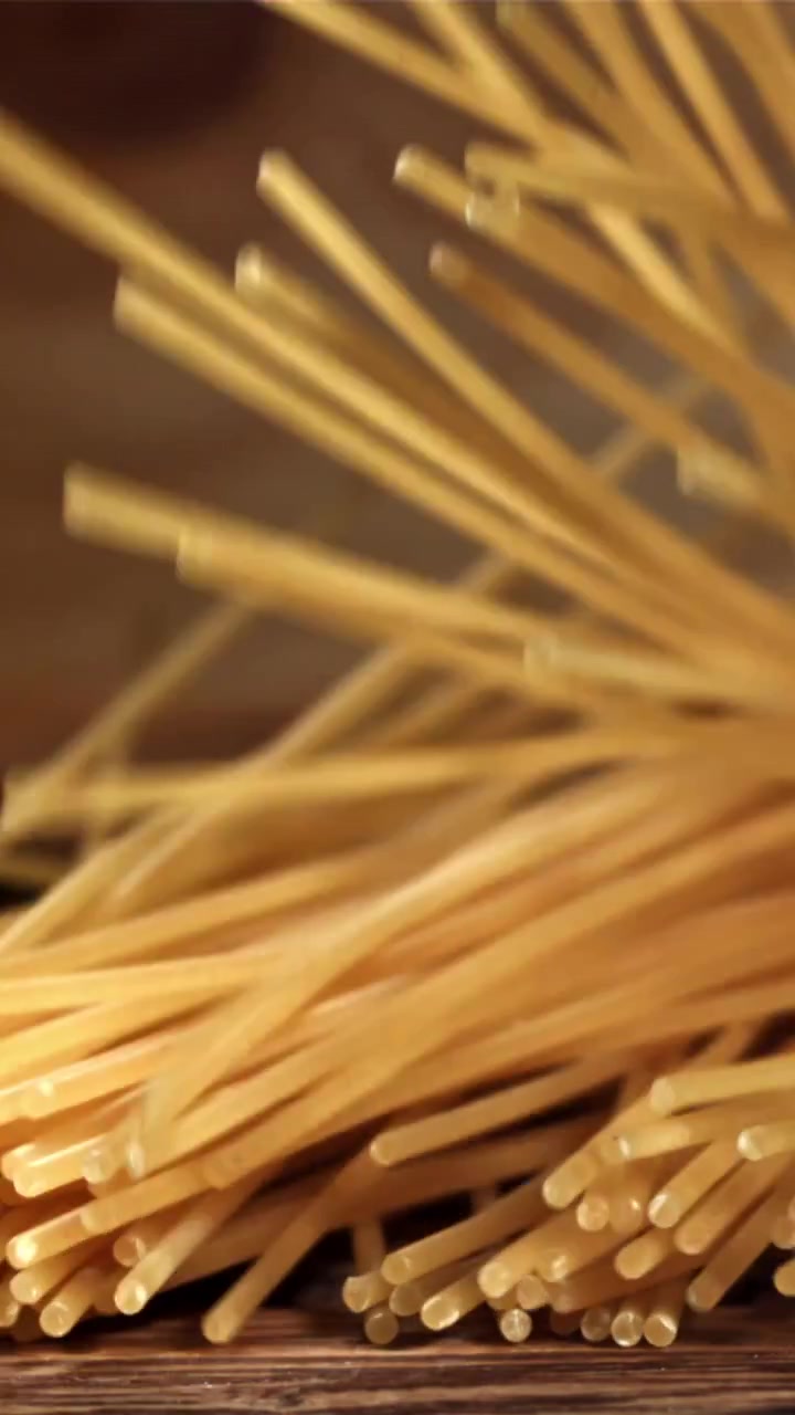Espaguetis secos cayendo a cámara lenta sobre una superficie de madera