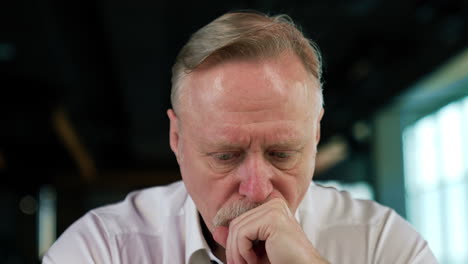 focused strict serious face of a senior caucasian man with fair hair in glasses. portrait of a tired pensive businessman taking off his glasses thinking hard. close up.