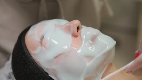 mujer hermosa con máscara facial en un salón de belleza