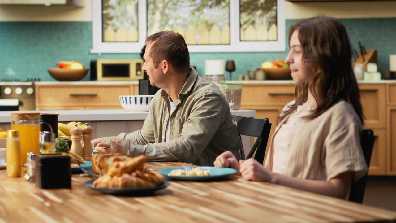 Happy family enjoying homemade breakfast in the kitchen and serving eggs
