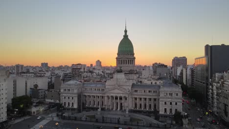 aerial rising over argentine congress palace with balvanera buildings in background at golden hour in busy buenos aires