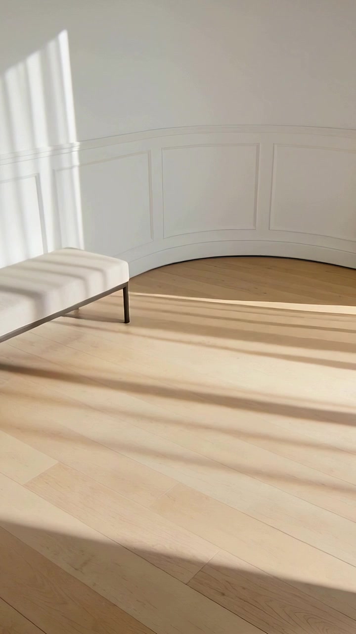 Vertical video: Panning shot revealing low bench in sunny hall with wall and light bands