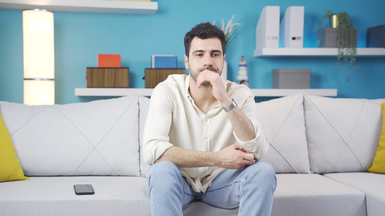 Giovane uomo depresso e preoccupato seduto da solo sul divano a casa