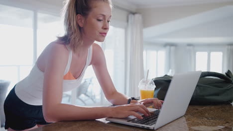 mujer joven descargando datos del rastreador de salud personal al portátil después del ejercicio