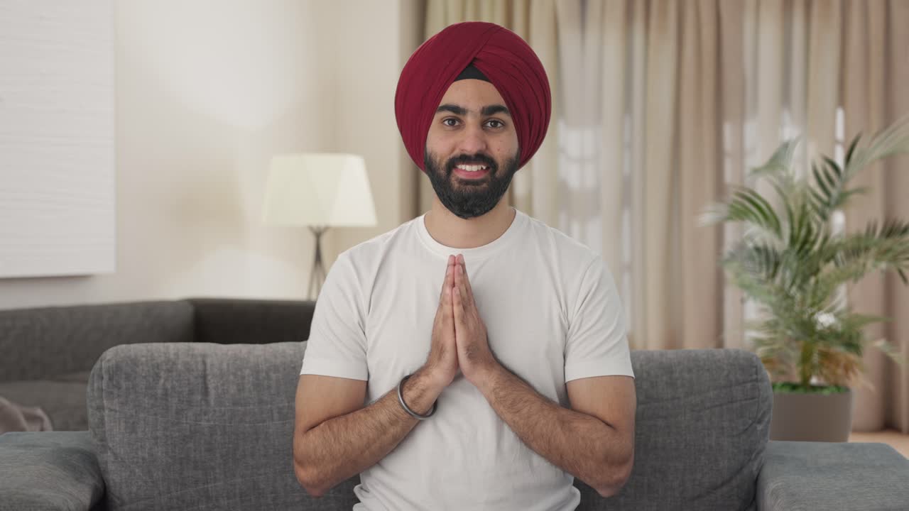 Uomo indiano Sikh felice che fa Namaste