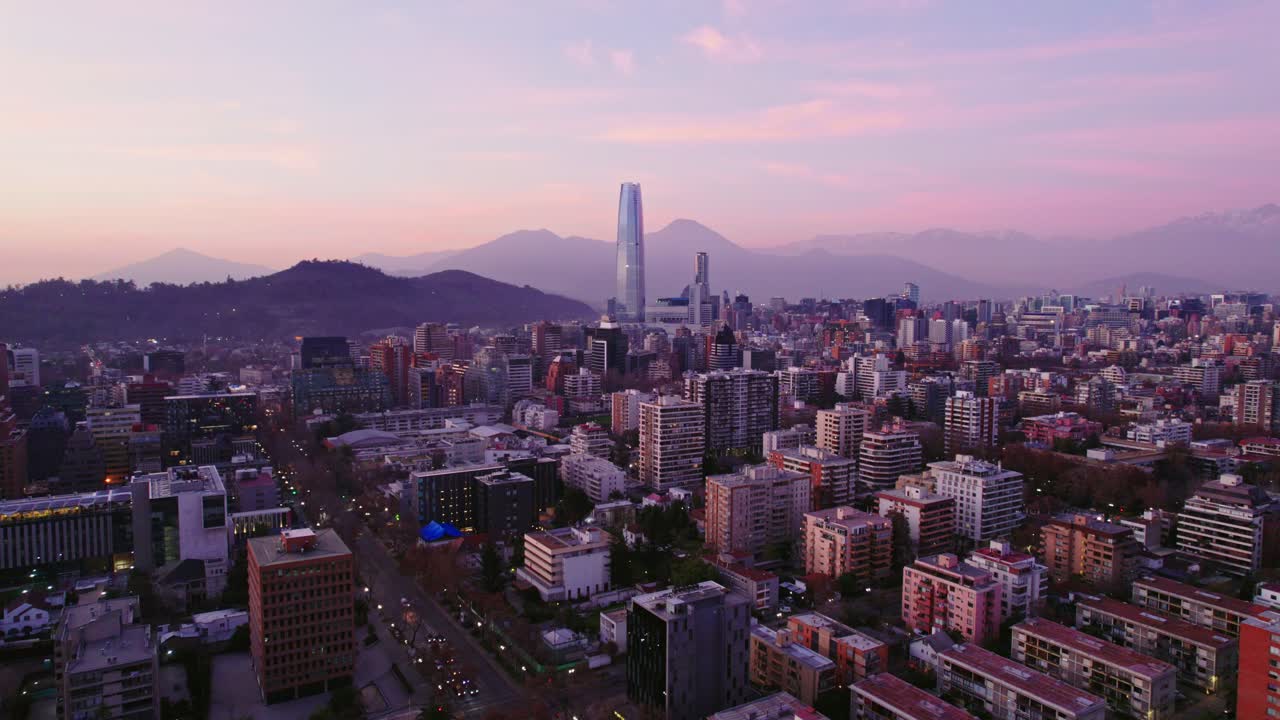 Aerial view dolly out establishing of Santiago Chile in Providencia residential neighborhood and financial center with the Costanera tower at sunset in the background