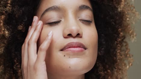 biracial woman with dark hair touching face on beige background, slow motion