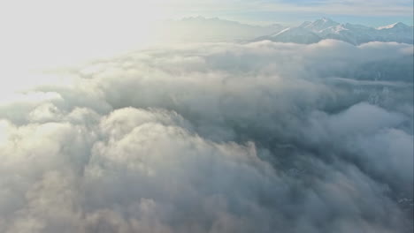 white fluffy clouds above mountain range, aerial drone high altitude view