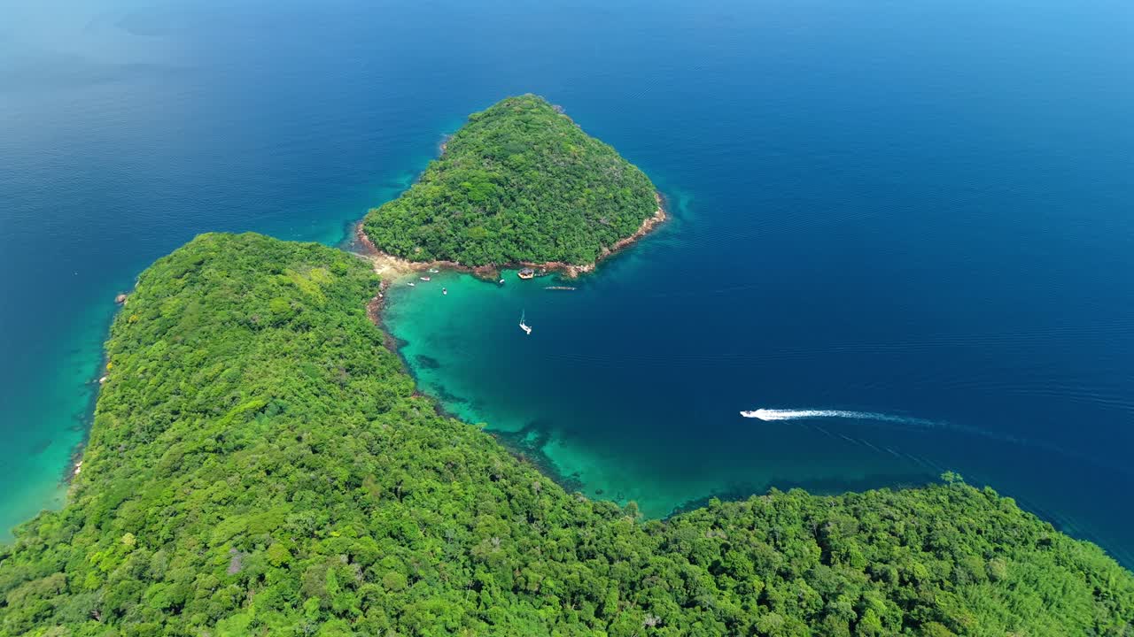 Rekaman drone udara yang menakjubkan dari Lagoa Verde yang masih alami di Ilha Grande, Angra dos Reis. Sebuah speedboat menavigasi perairan pesisir biru tua Brasil.