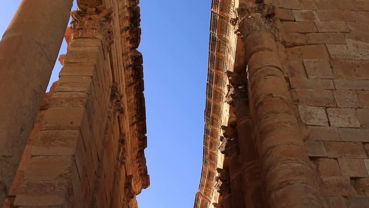 tomada de ángulo bajo de las ruinas romanas de sbeitla contra un cielo azul claro, la cálida luz del sol iluminando las antiguas piedras