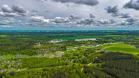 forest village landscape with dramatic clouds and meandering river in aerial timelapse