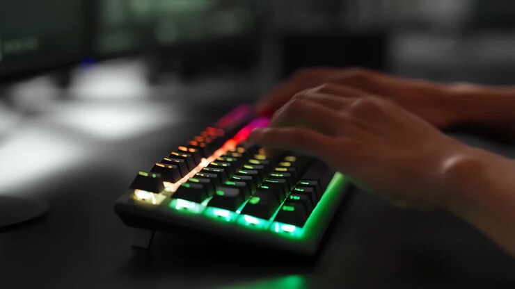 Mani che digitano su una tastiera da gaming RGB luminosa