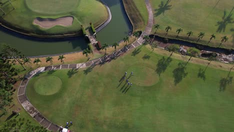 drone shot from above, top to bottom footage shows a golfer taking a tee shot