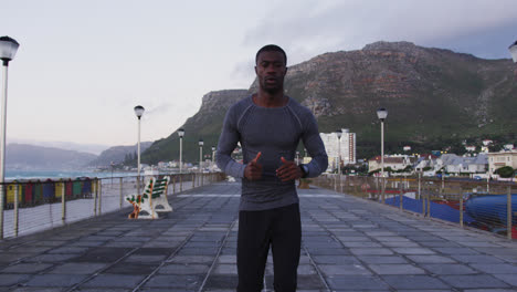 focused african american man exercising outdoors, running by seaside