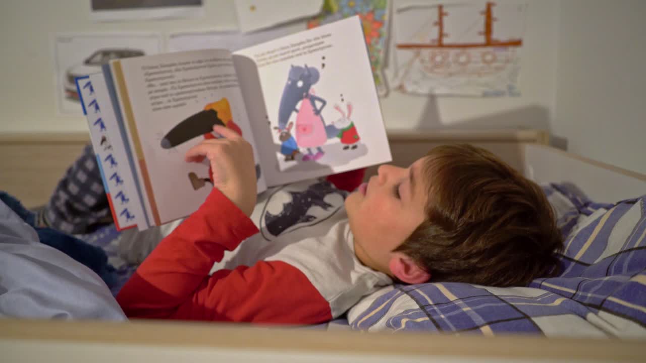 vista lateral media de un niño caucásico leyendo un cuento de hadas antes de dormir 4k